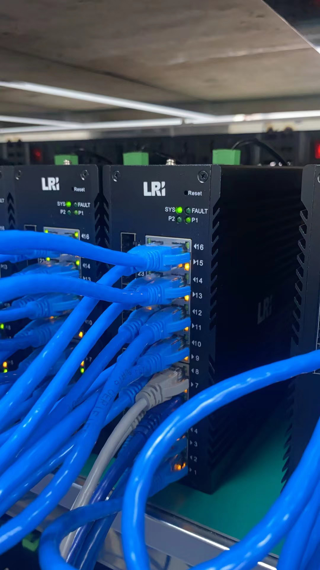 Switch de automação industrial com cabos azul conectados, componentes LRI para controle de sistemas automatizados, promovendo eficiência e integração na manufatura.